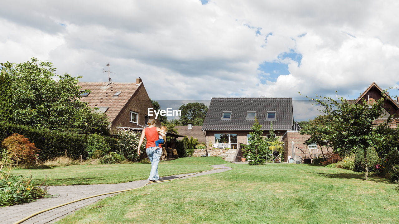 Woman with son walking on field in yard