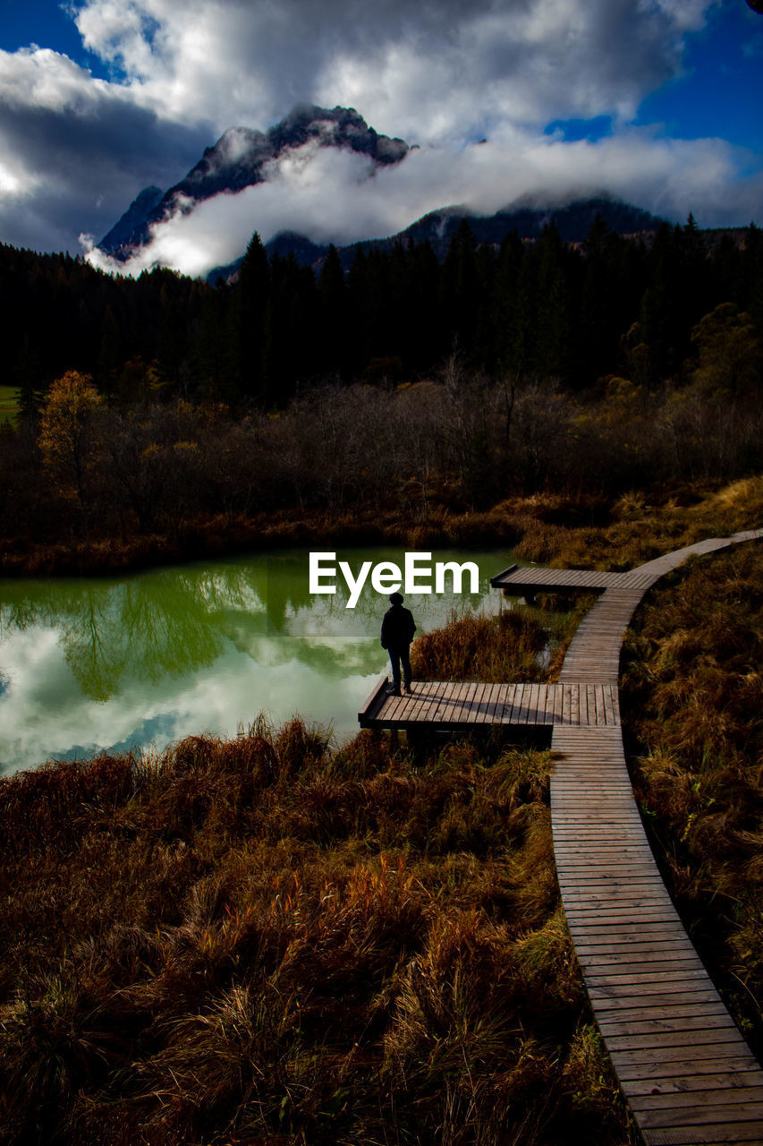 Young man standing by lake during autumn