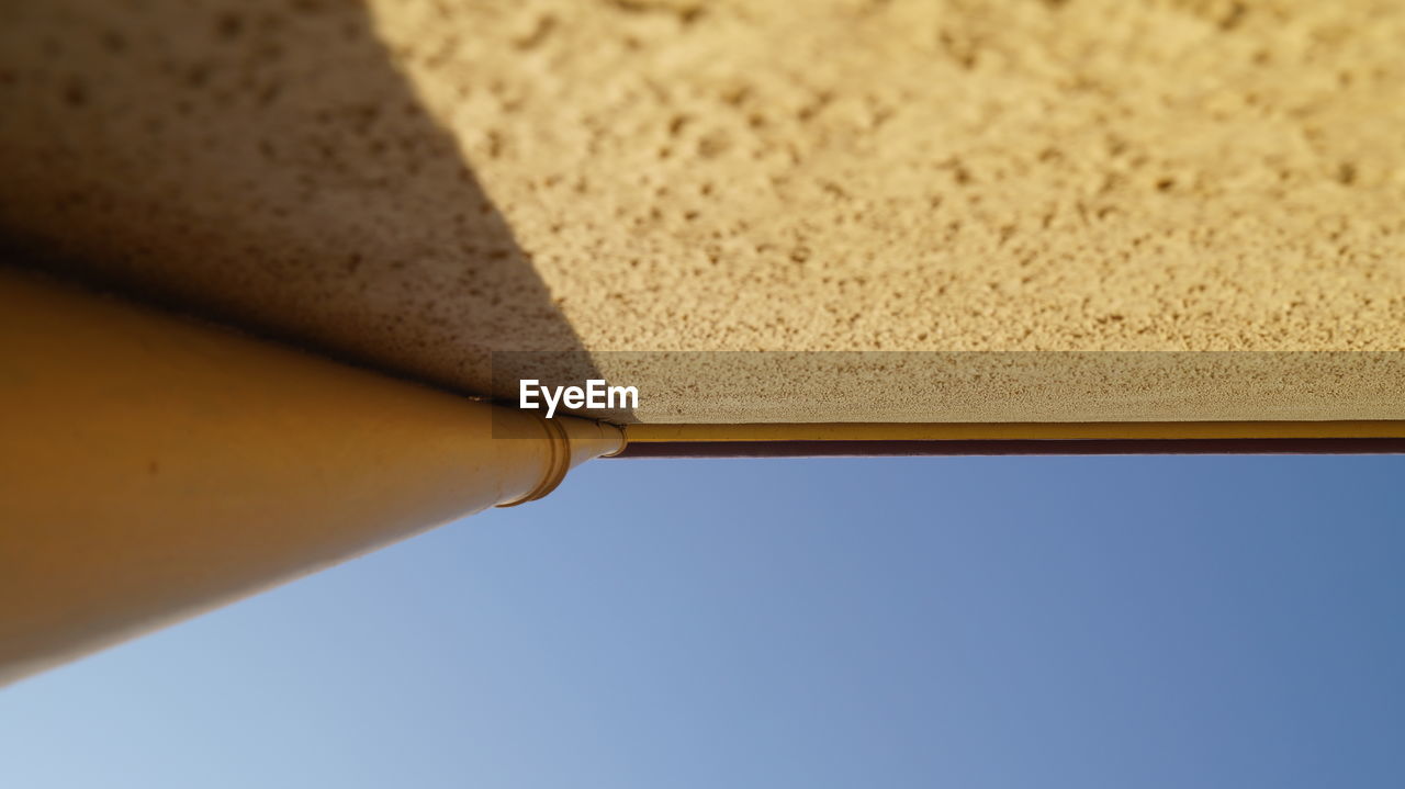 Directly below shot of pipe on wall against clear sky