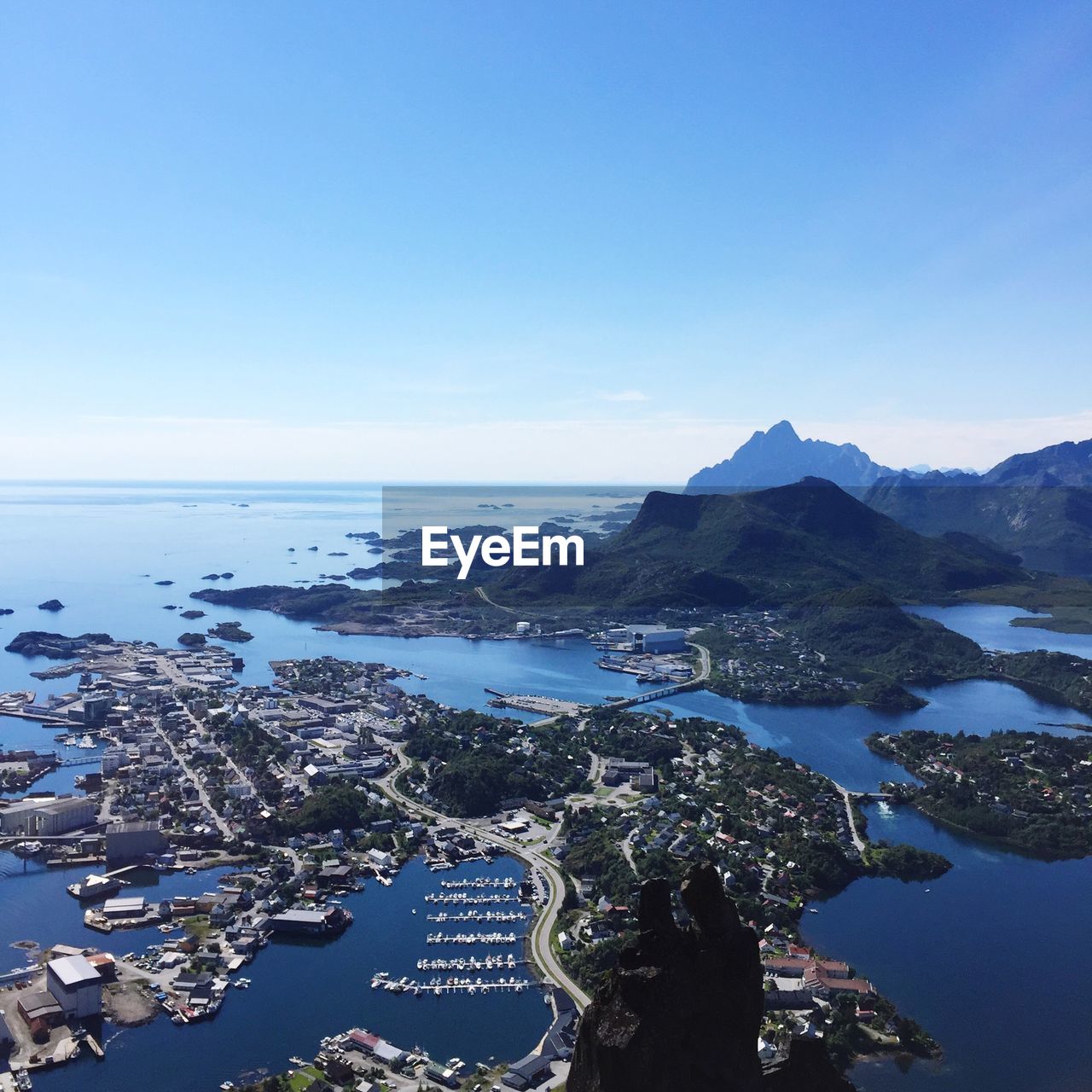 Aerial view of city by sea against clear blue sky