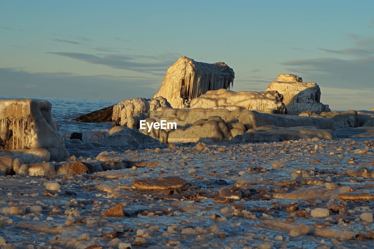 Rock formations on sea shore against sky