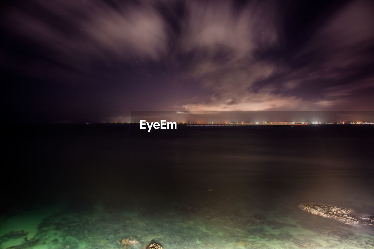 Scenic view of sea against cloudy sky at night