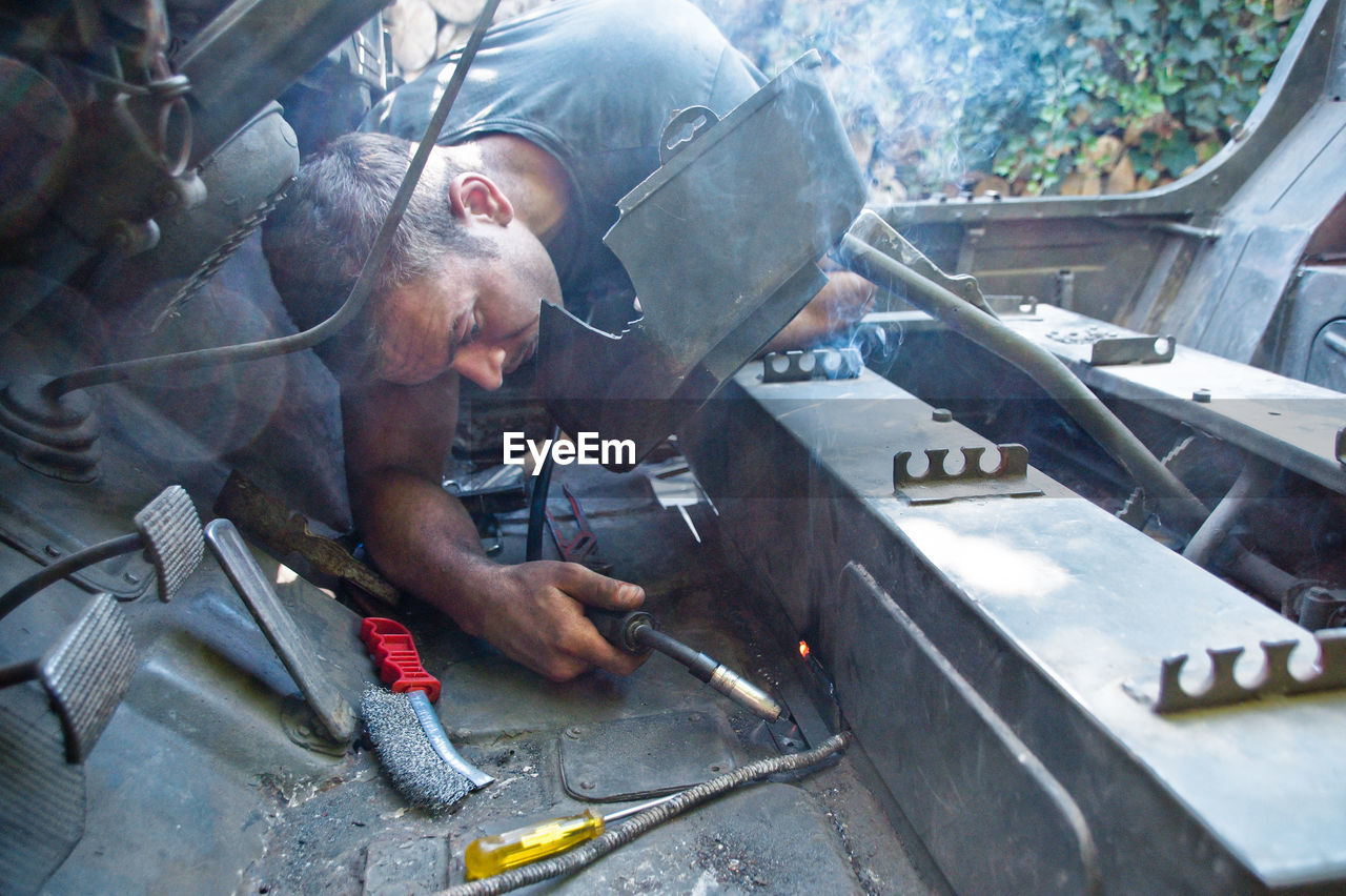 Young man welding metal in car