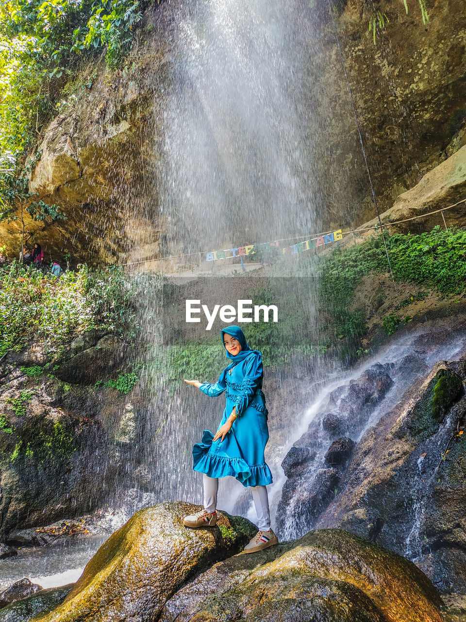 Woman standing by waterfall in forest