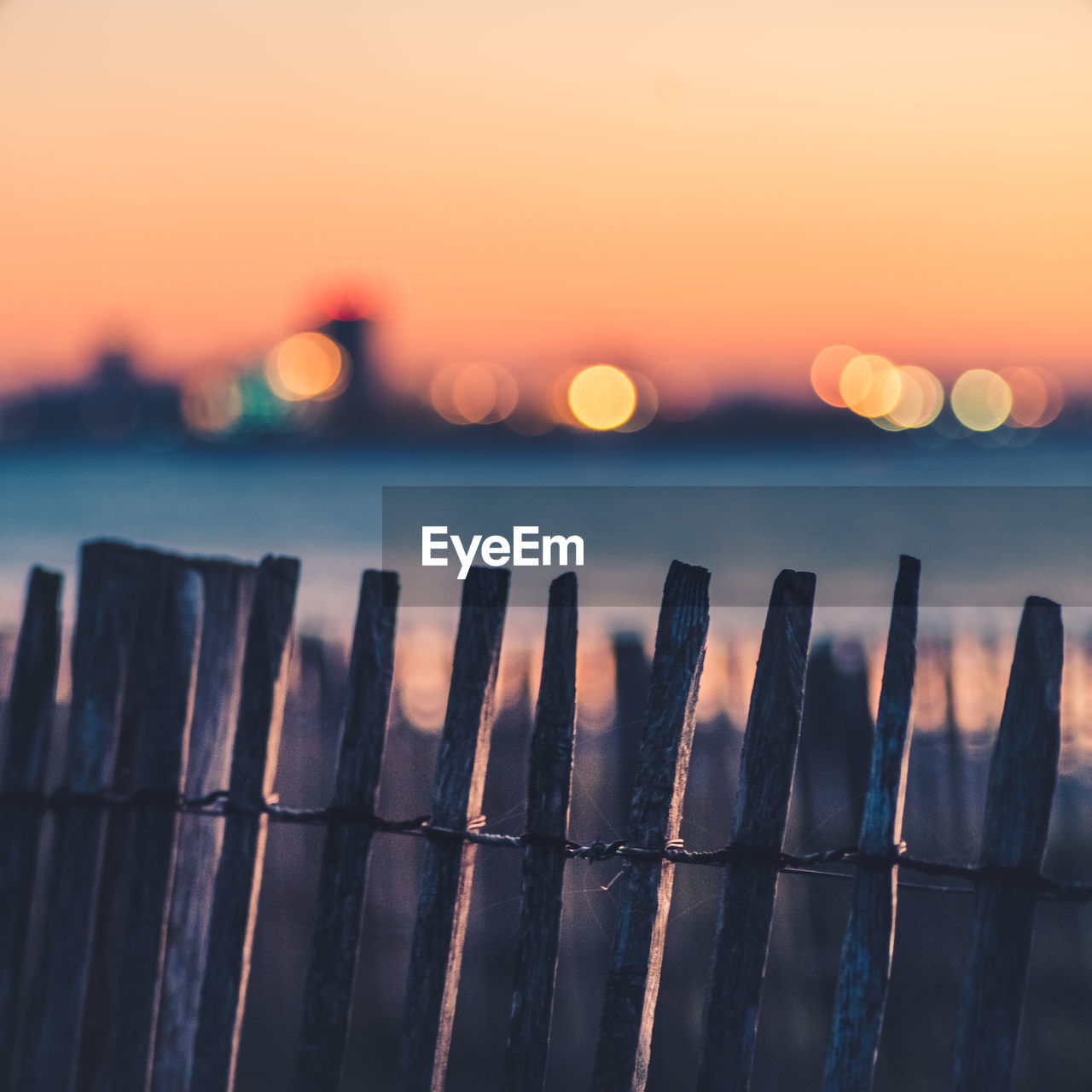 sunset, sky, reflection, sunlight, nature, water, no people, fence, dusk, sea, horizon, sun, tranquility, evening, outdoors, twilight, architecture, beauty in nature, scenics - nature, light, focus on foreground, land, orange color, close-up, urban skyline, security, landscape, blue, tranquil scene, protection