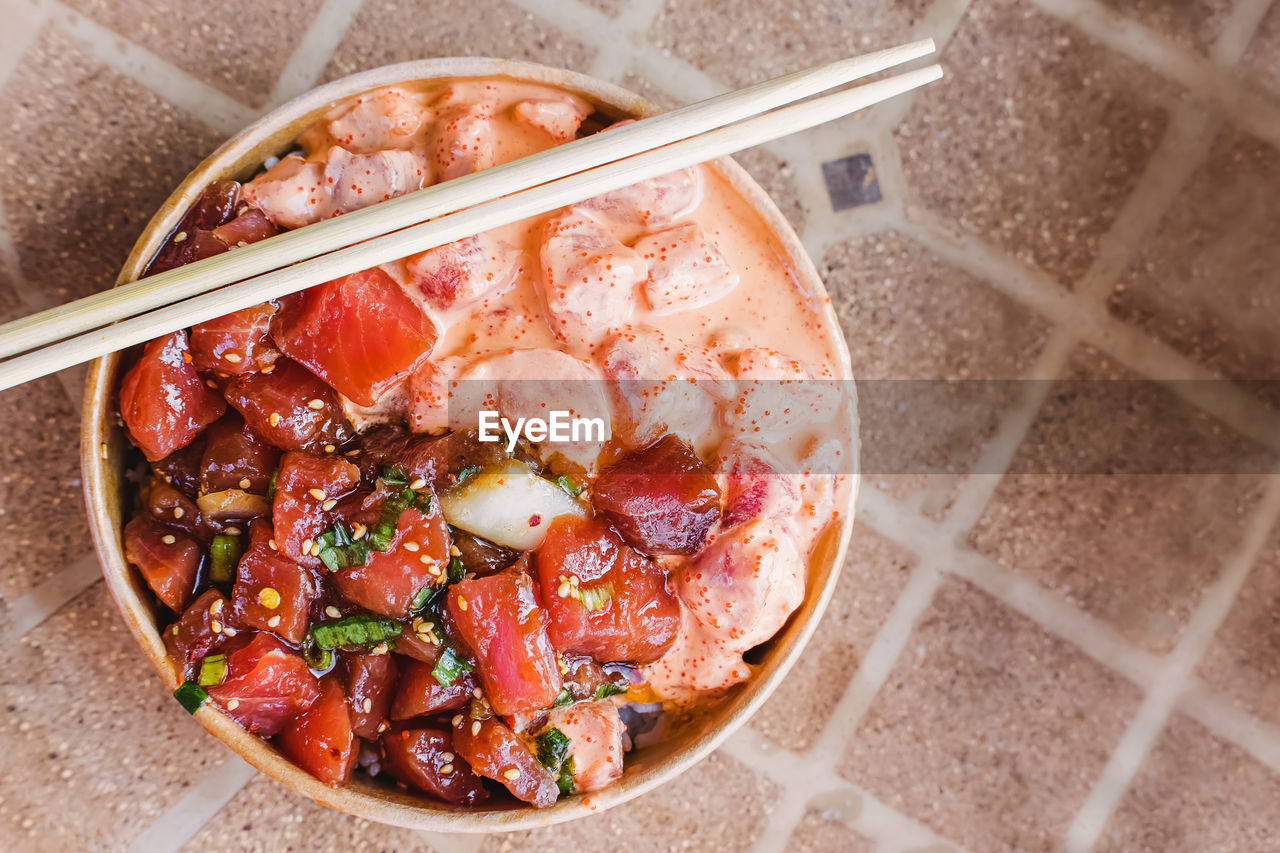 Two types of delicious traditional hawaiian poke in a paper bowl, top view