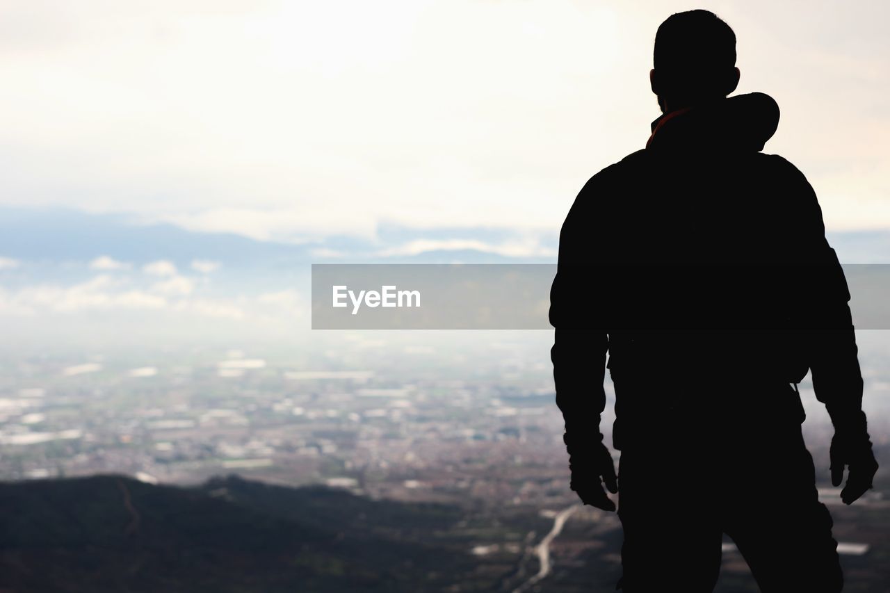 Rear view of man standing against cityscape 