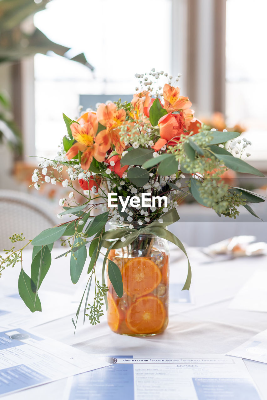 Soft focus orange themed flower arrangement on a banquet table