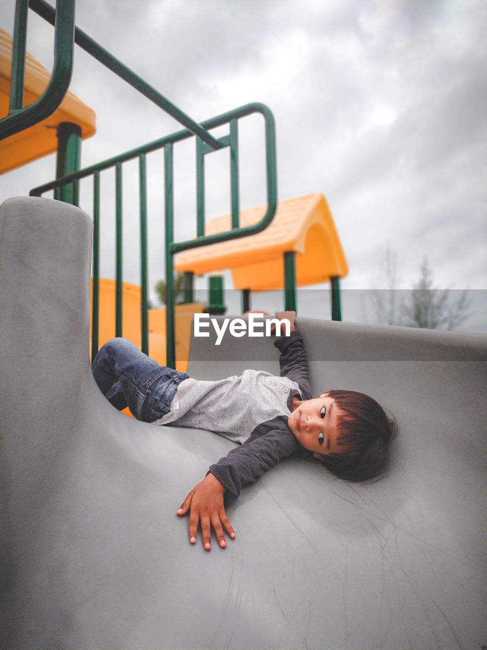Boy lying on slide at playground