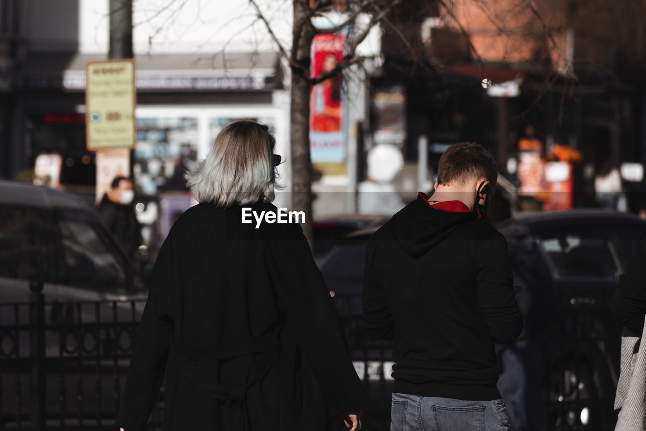 REAR VIEW OF PEOPLE ON STREET IN CITY