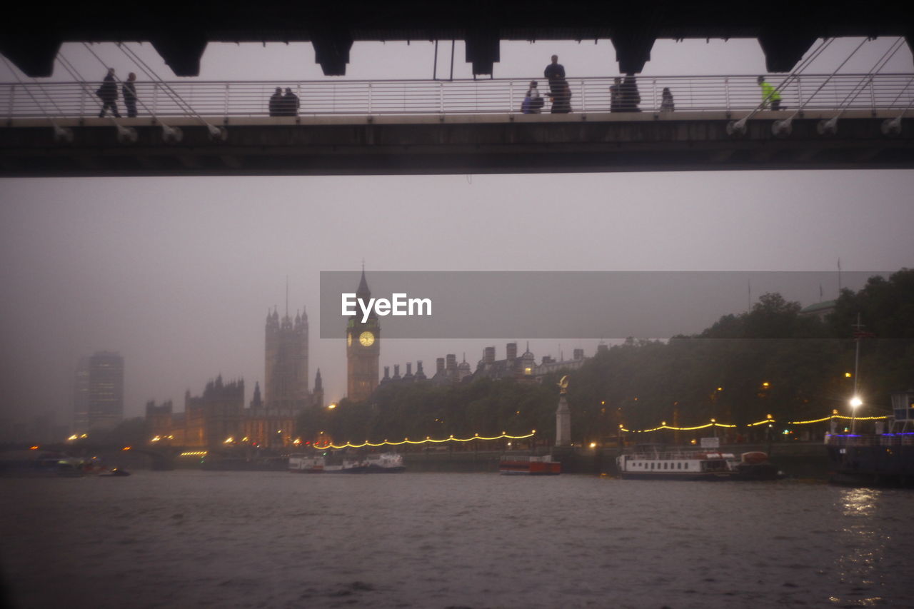 Low angle view of people on bridge over river with big ben in background