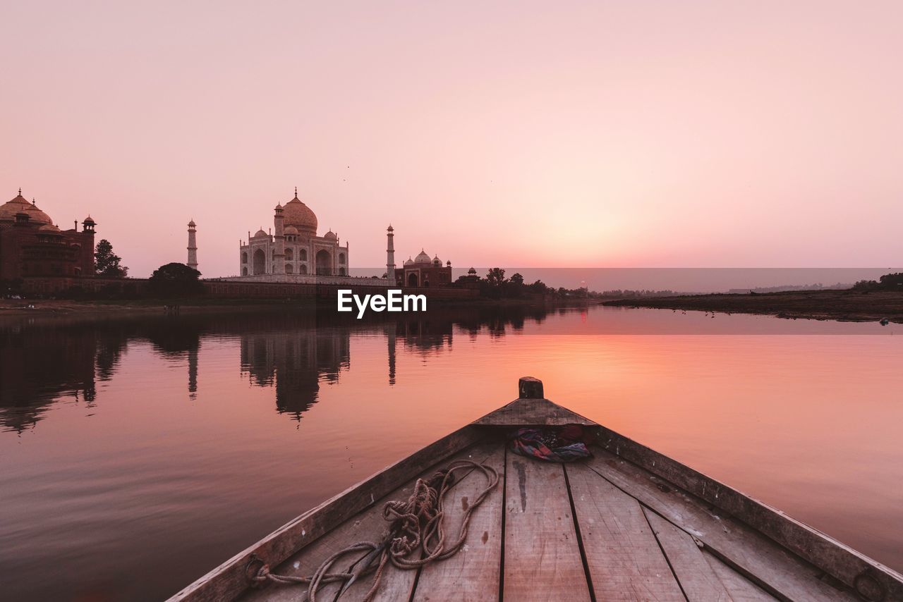 Boat in lake during sunset against taj mahal