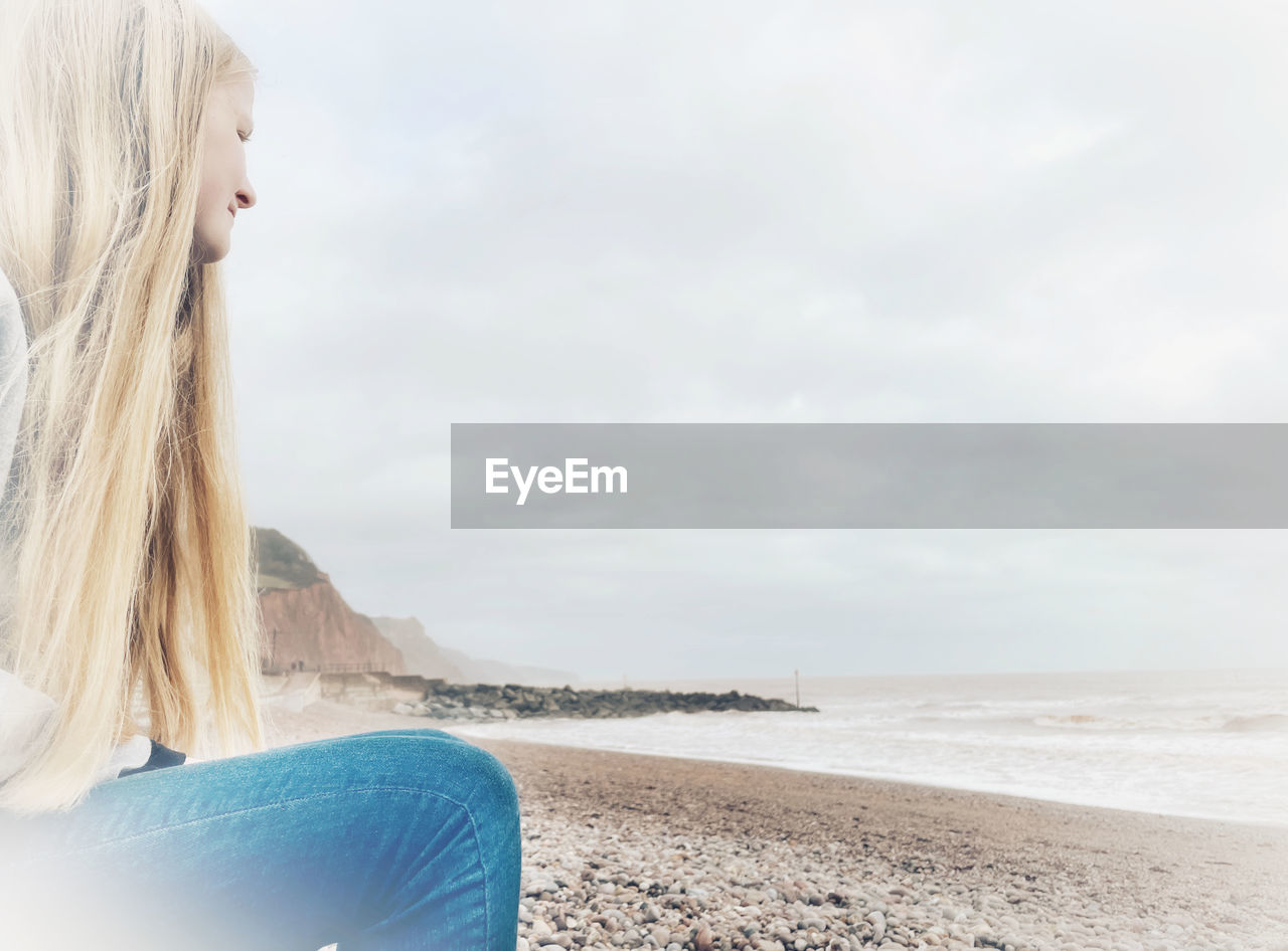 WOMAN AT BEACH AGAINST SKY