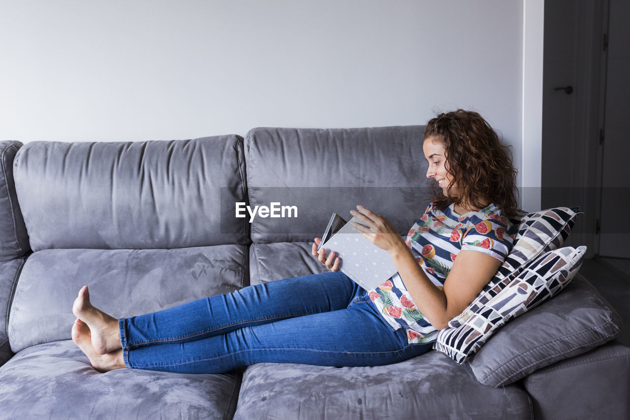 Woman reading diary while sitting on sofa at home