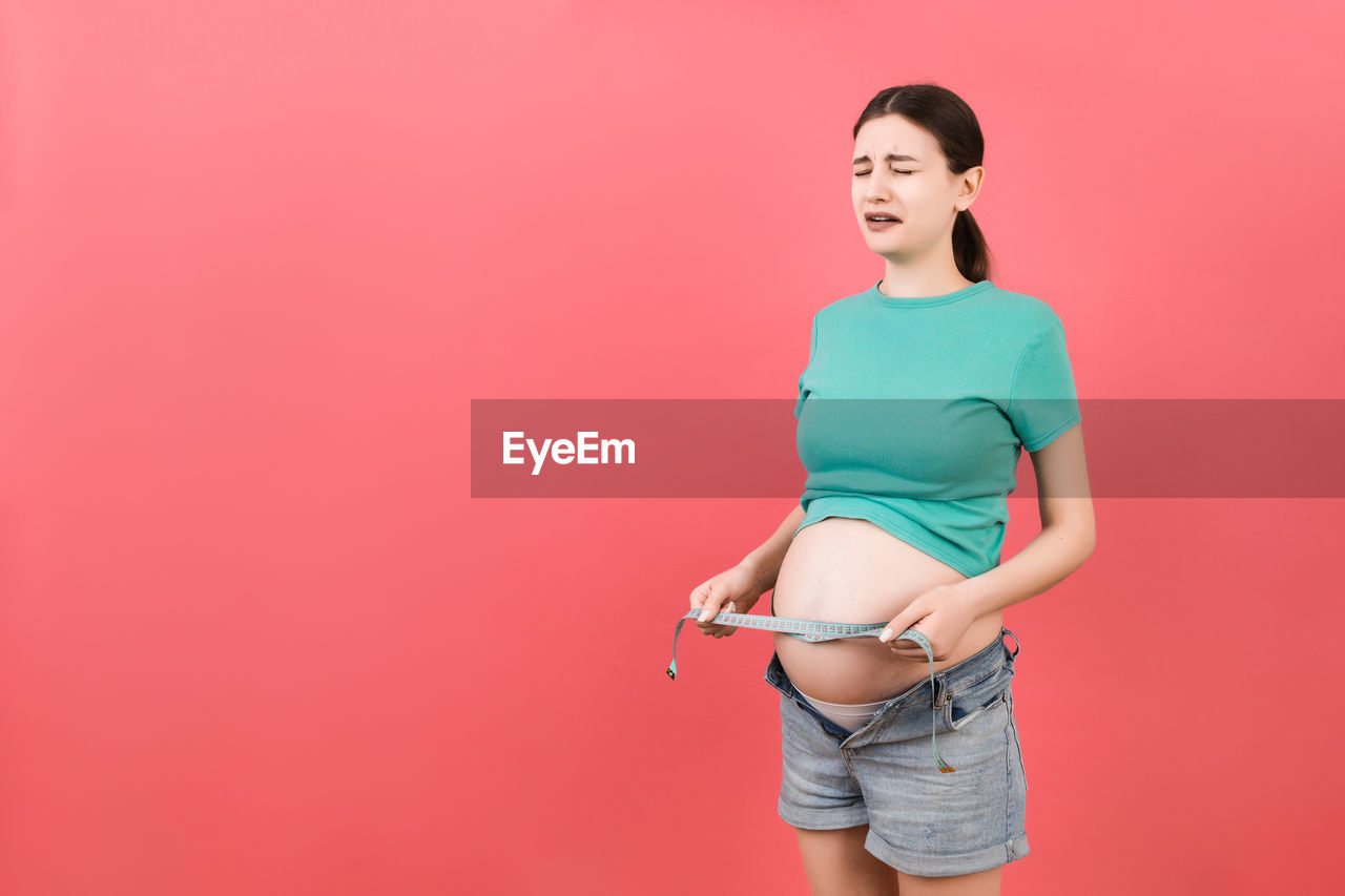 WOMAN STANDING AGAINST PINK BACKGROUND