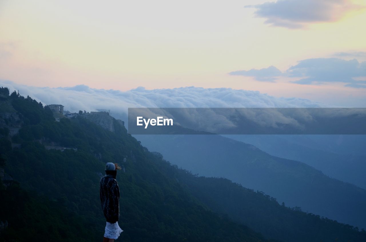 Rear view of woman standing on mountain against sky