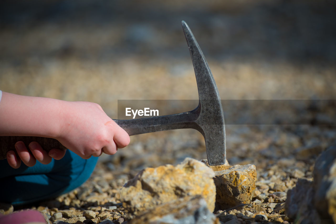 Close-up of hand hammering rock with equipment