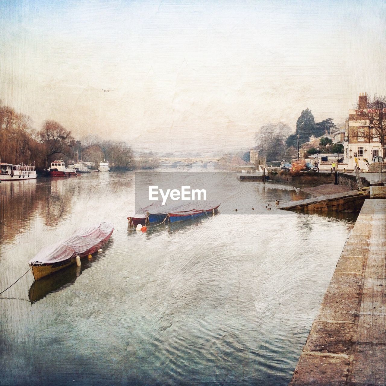 Moored boats in river with buildings in distance