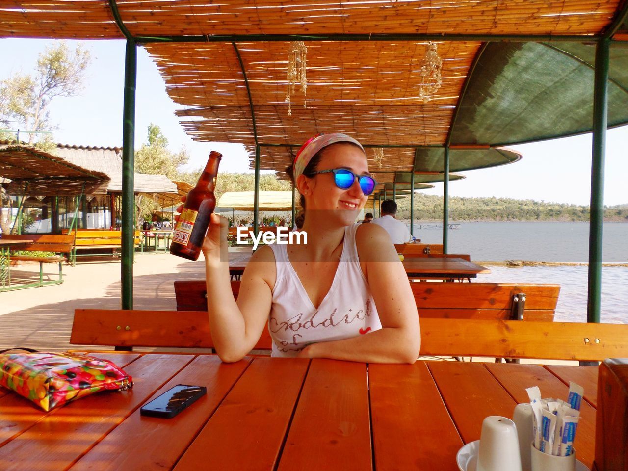 Young woman sitting at outdoor cafe with beer bottle