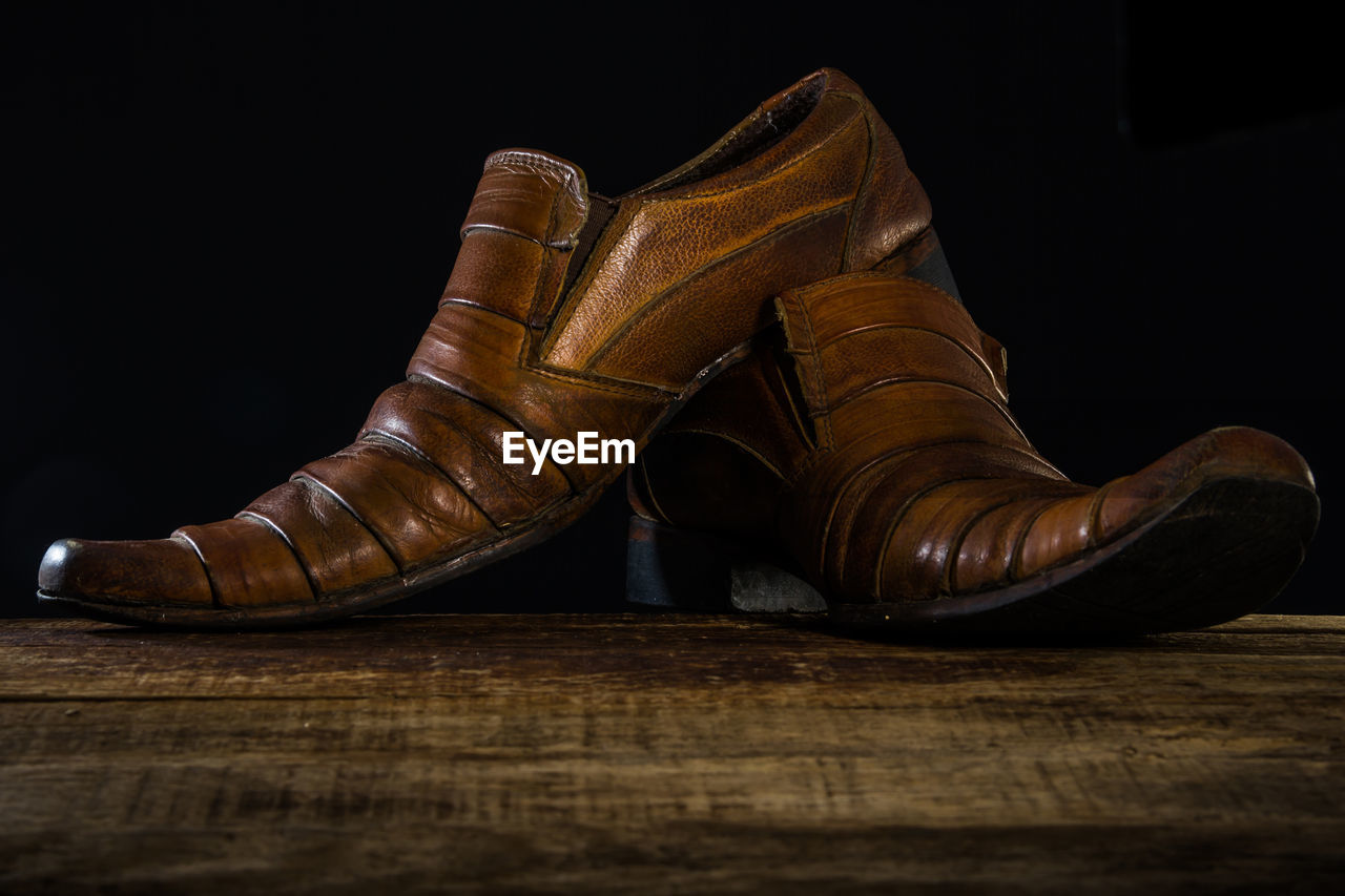 CLOSE-UP OF SHOES ON WOODEN FLOOR