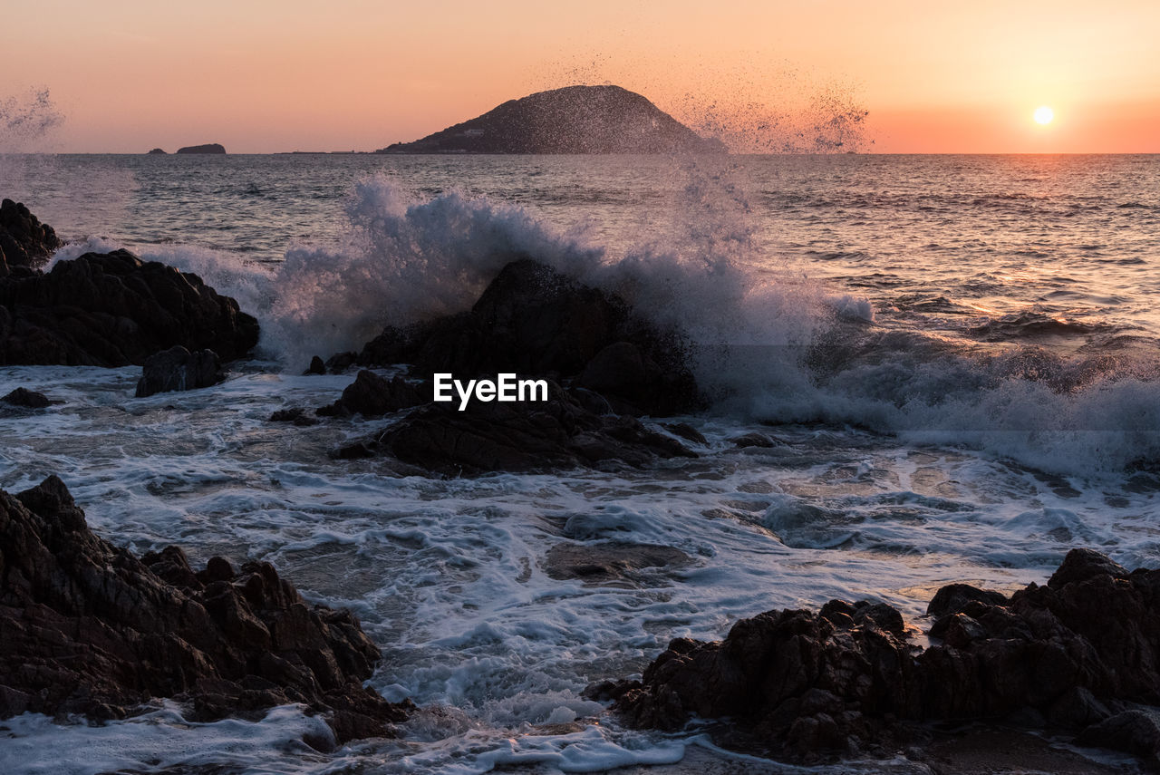 WAVES SPLASHING ON ROCKS AT SUNSET