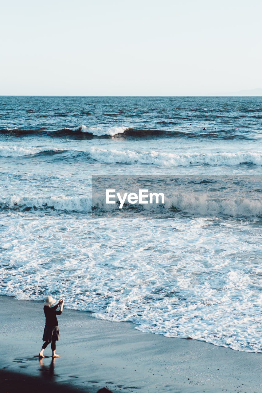 High angle view of woman standing at beach against clear sky