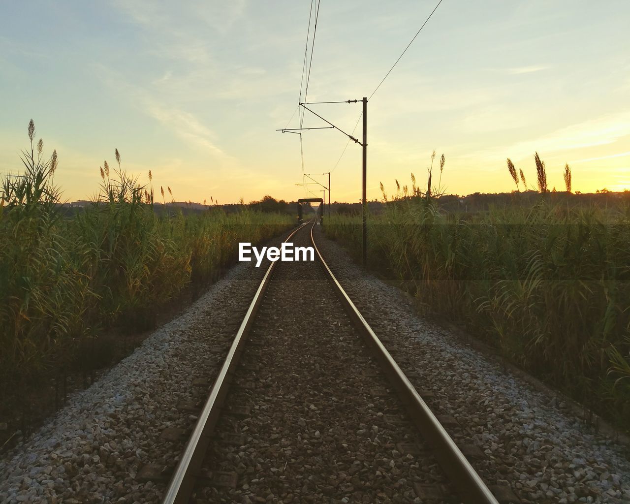 Railroad track against sky during sunset