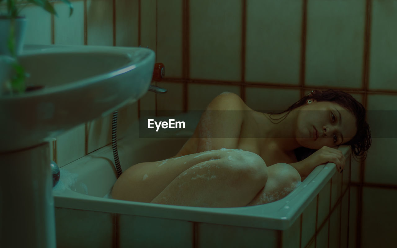 Portrait of young woman lying in bathroom