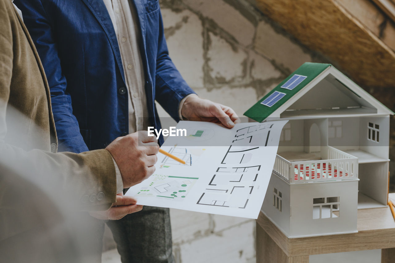 Businessman showing blueprint to colleague at construction site