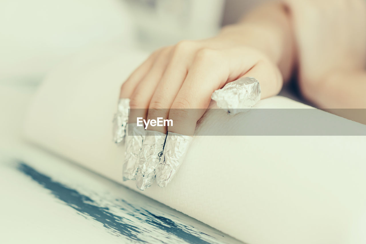 Close-up of woman fingers with wrapped in silver foil 