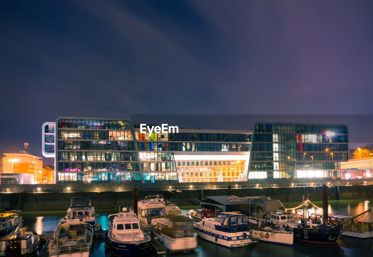 ILLUMINATED CITY BY RIVER AGAINST SKY