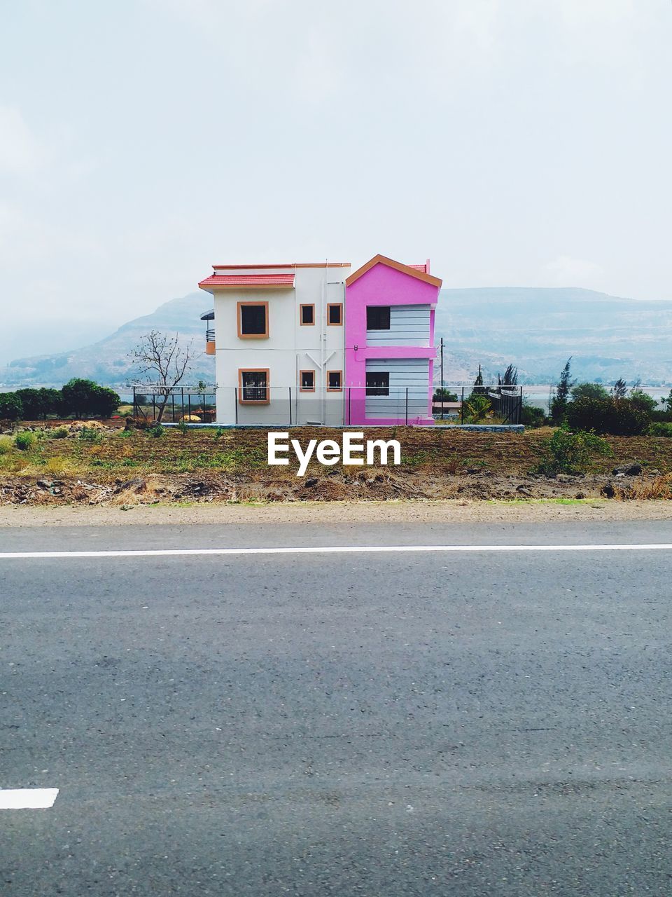 HOUSES BY ROAD AGAINST SKY