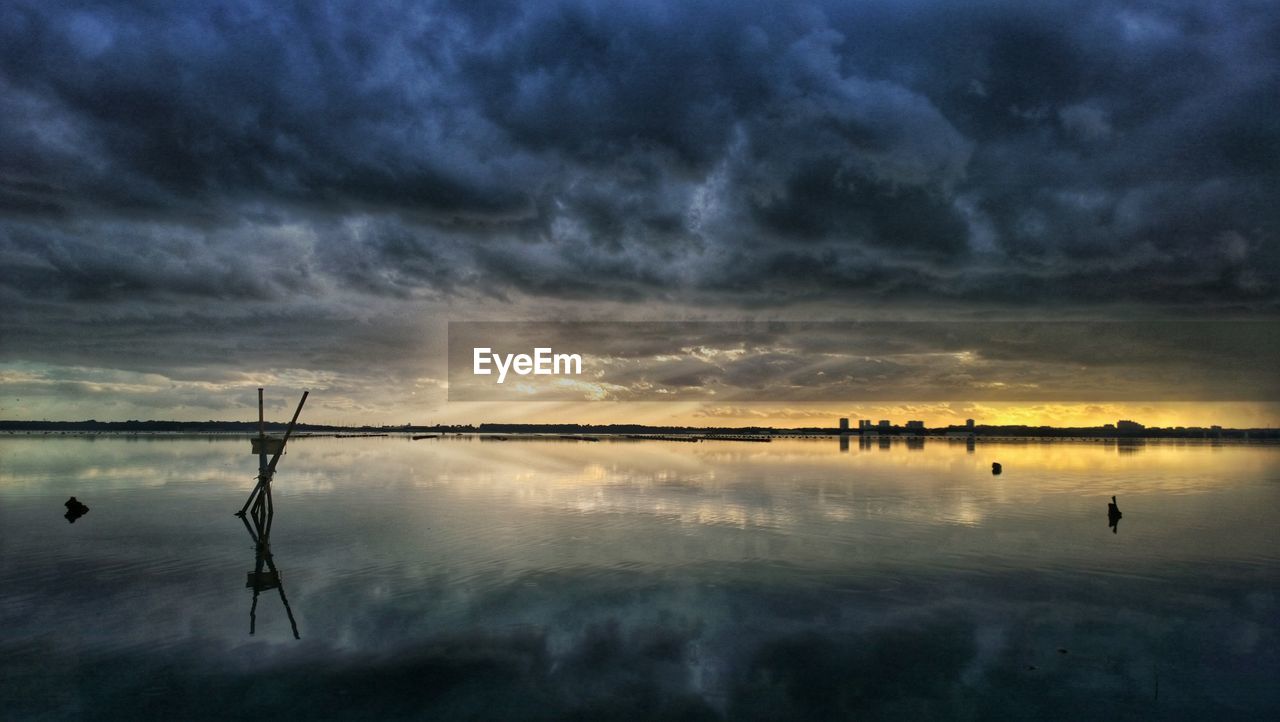 Storm clouds reflecting in sea during sunset