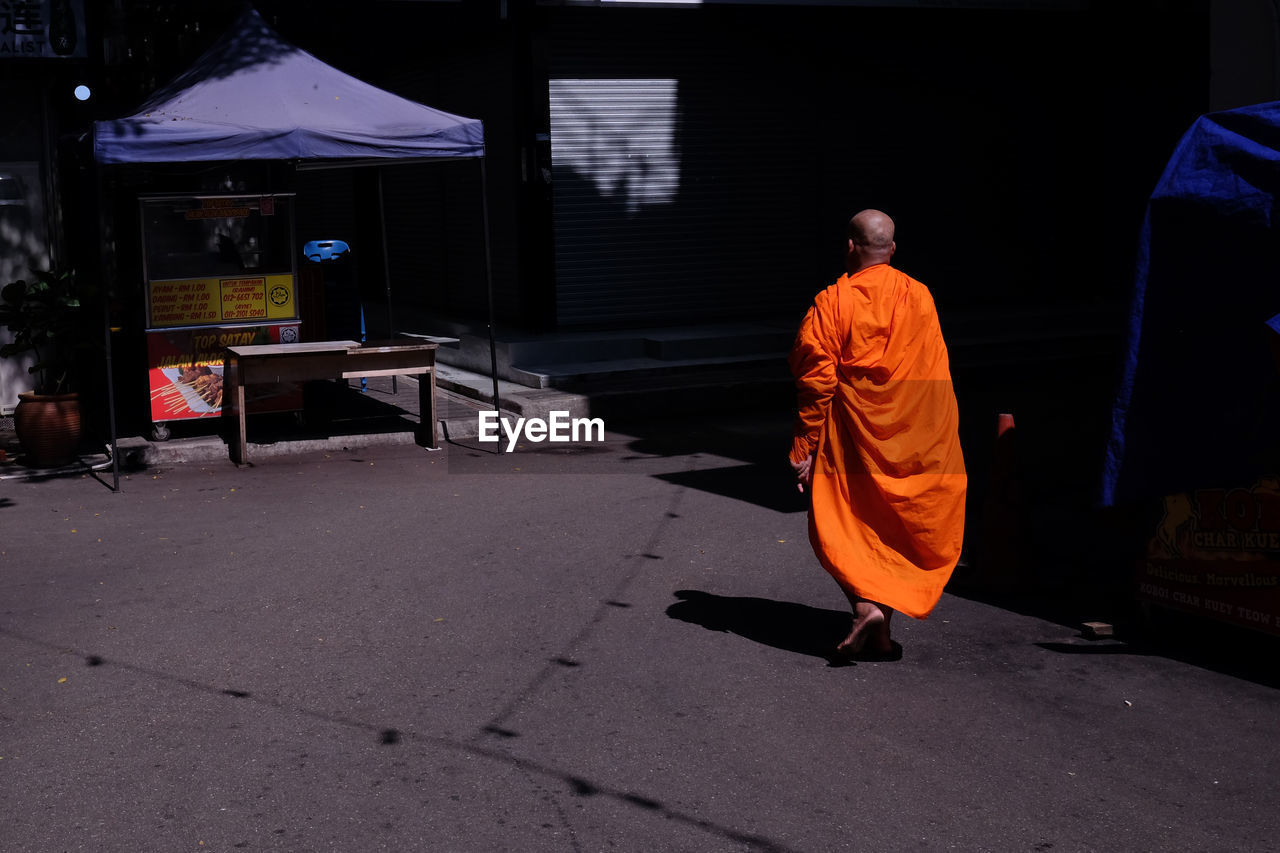 Rear view of monk walking on road