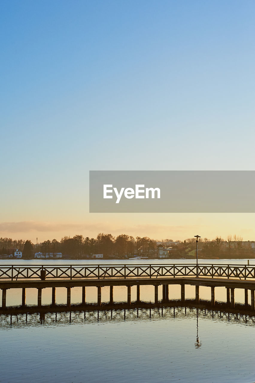 Bridge over water against clear sky during sunset
