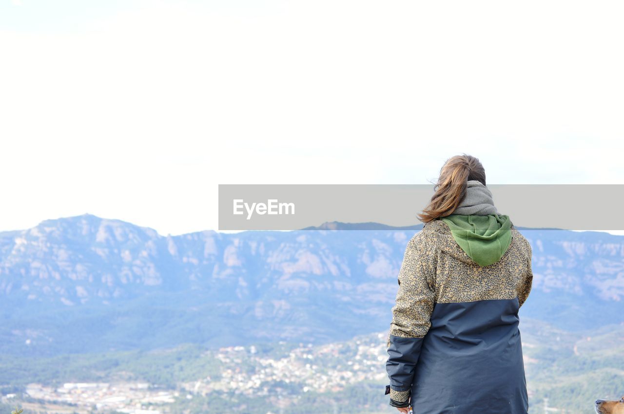 Rear view of woman standing on mountain against sky