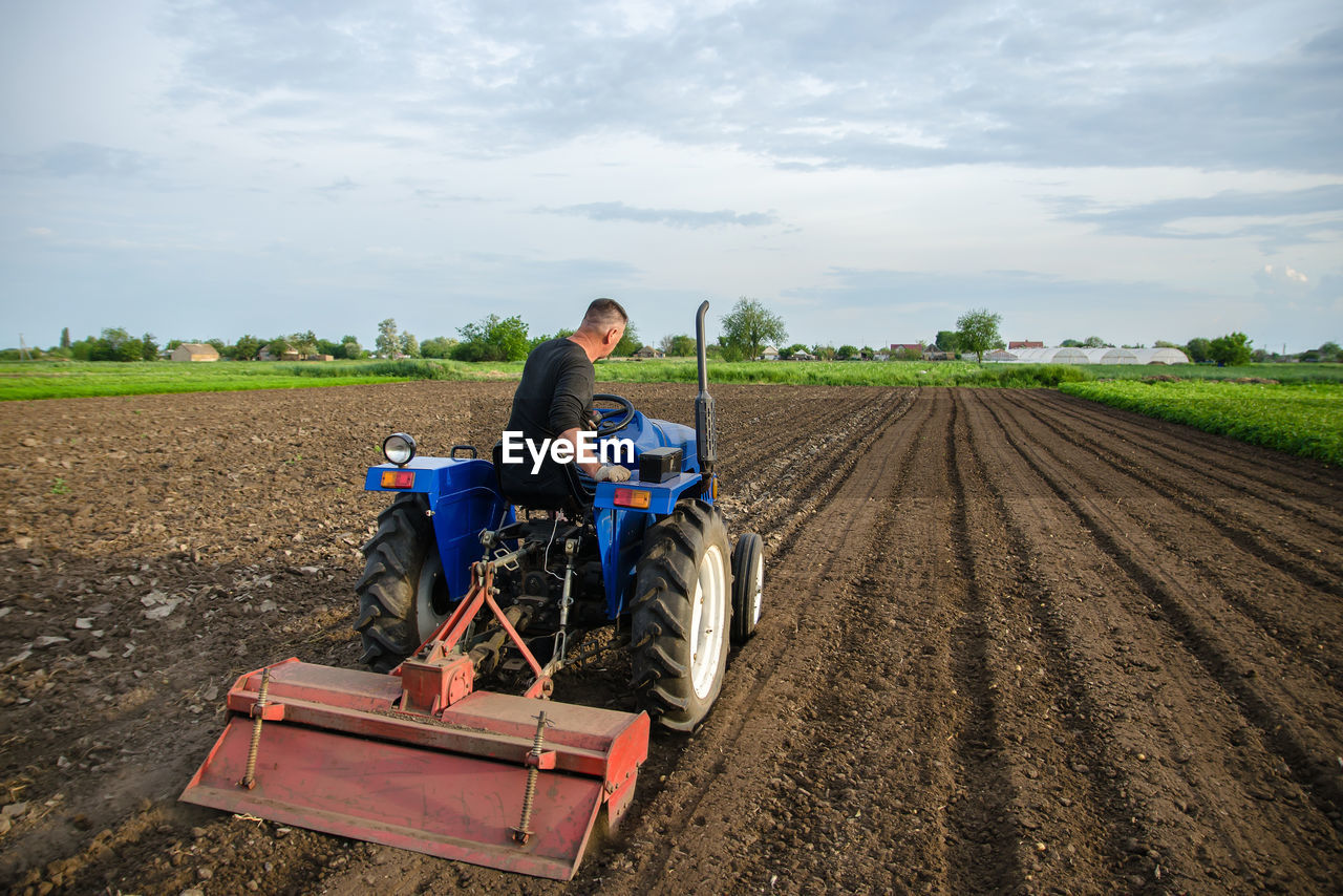 A farmer cultivates a field with a tractor after harvest. milling soil, crushing before cutting rows