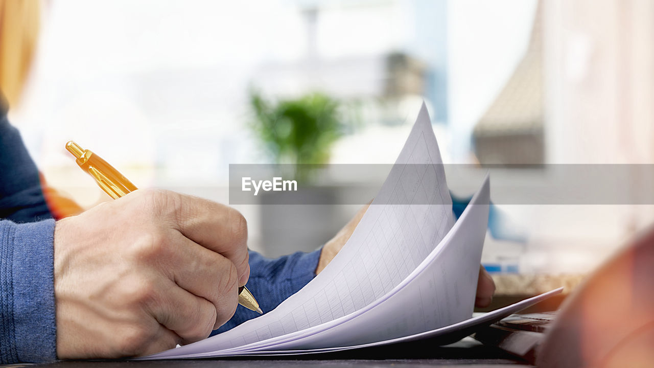 Close-up of businessman writing in book