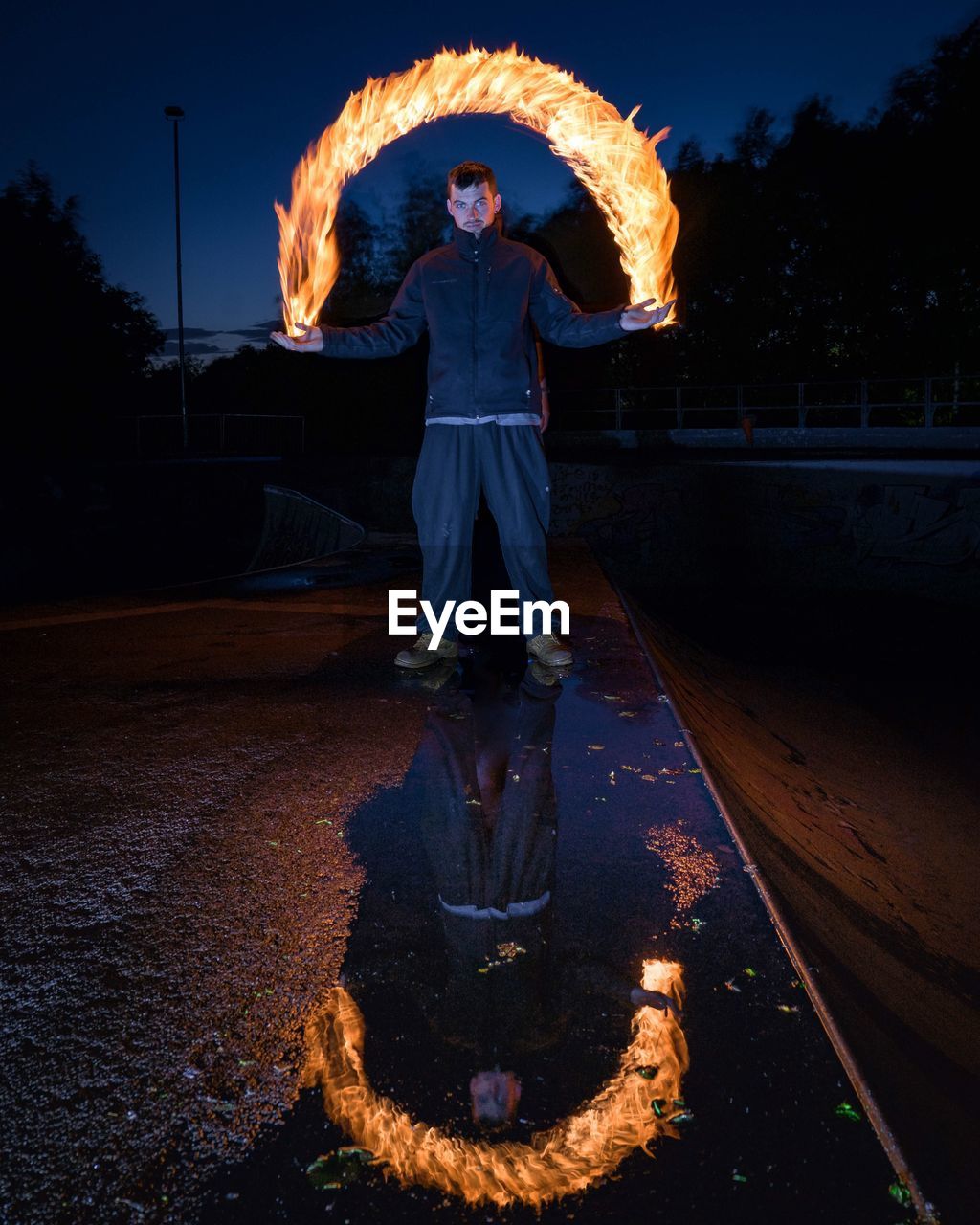 WOMAN STANDING BY ILLUMINATED STATUE AGAINST SKY