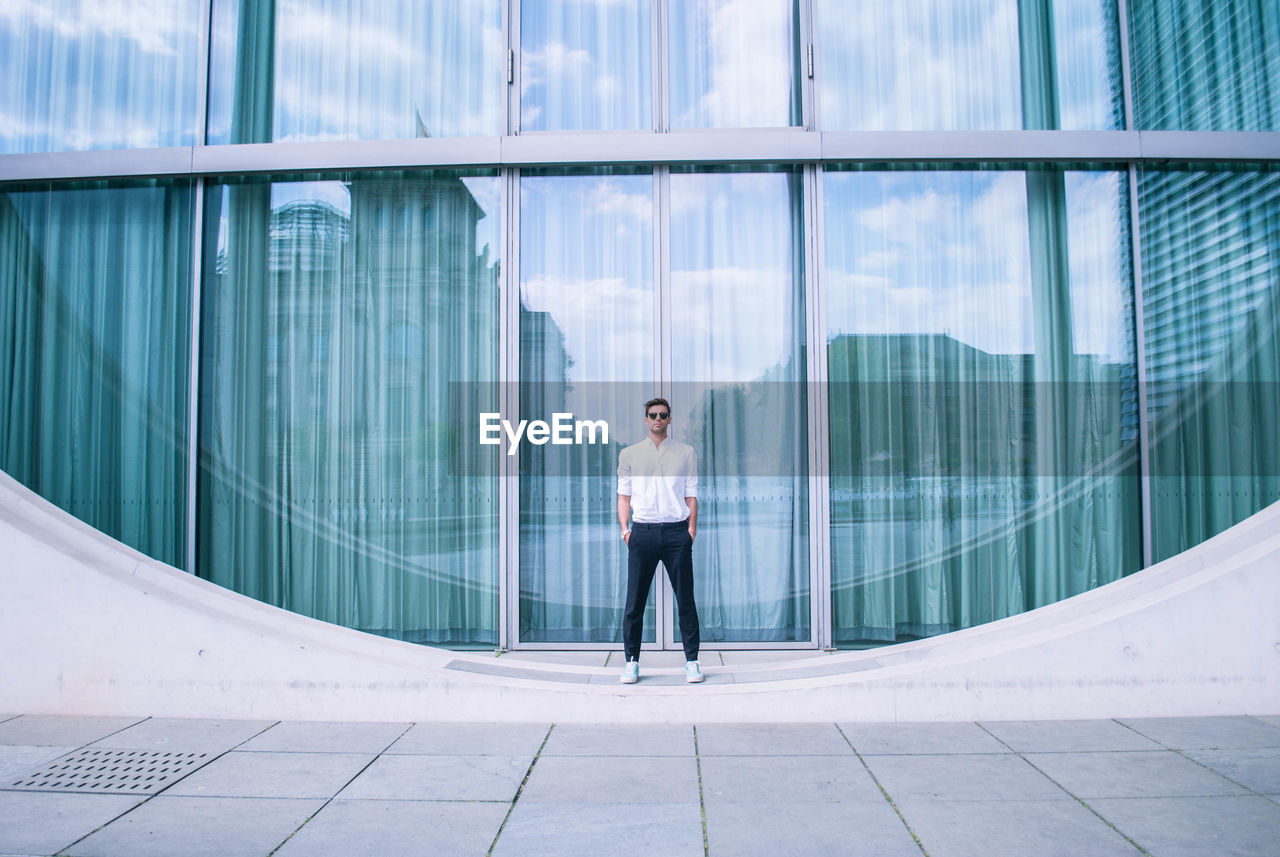 Full length of man standing by modern building