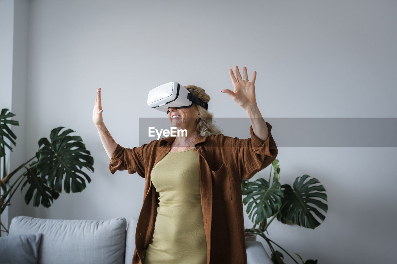 Smiling woman having fun wearing virtual reality headset at home