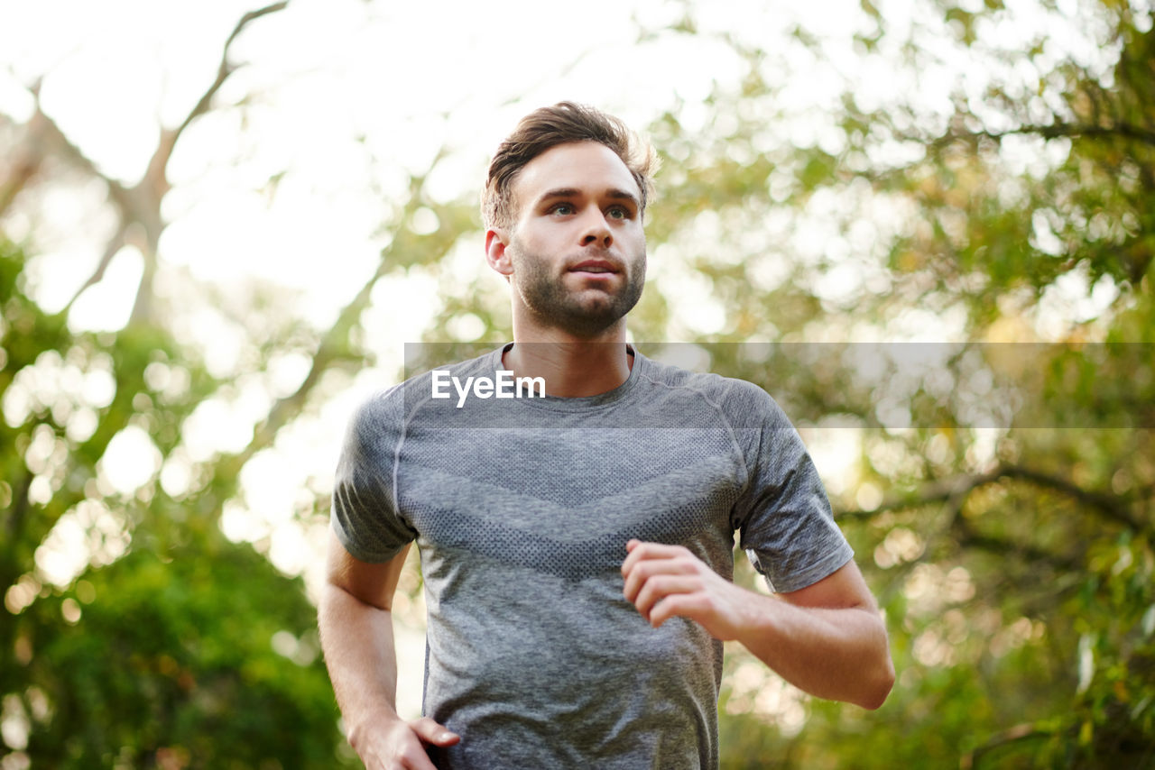 portrait of young man standing against tree