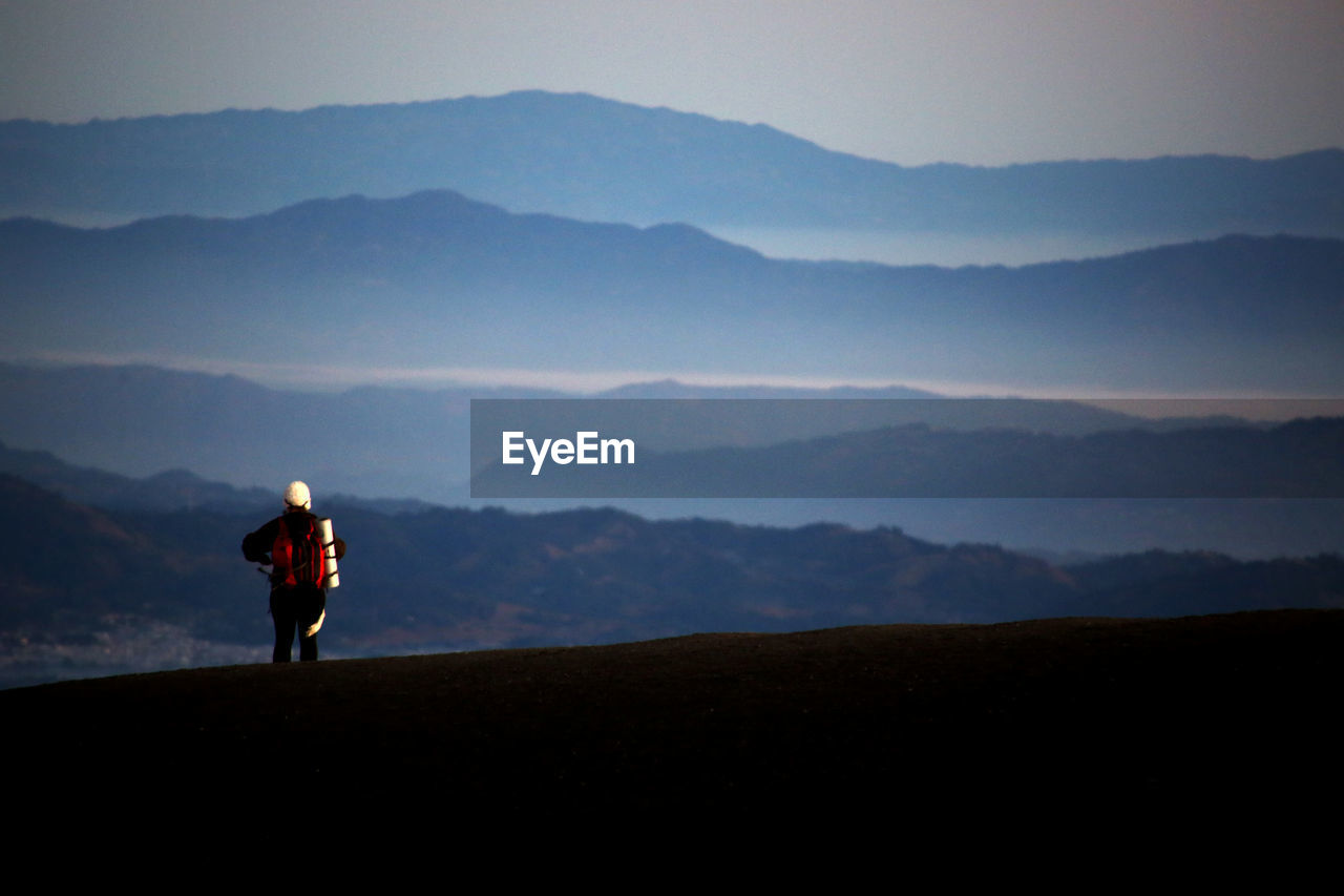 SILHOUETTE MAN STANDING ON LAND AGAINST SKY