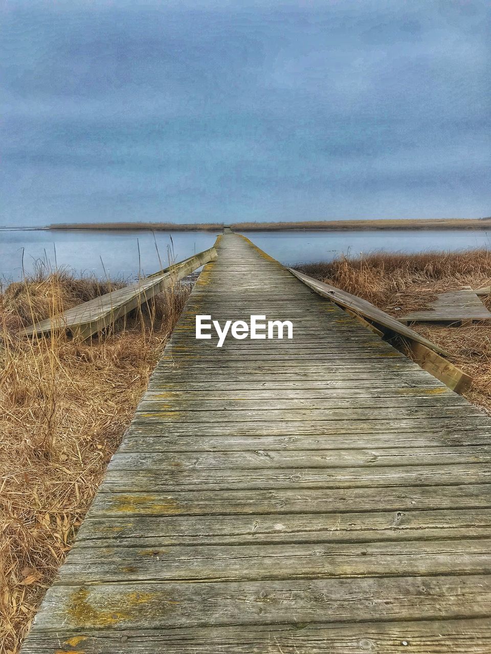 BOARDWALK AMIDST SEA AGAINST SKY