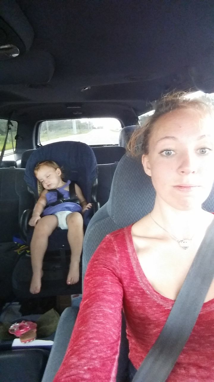 HAPPY YOUNG WOMAN SITTING IN CAR