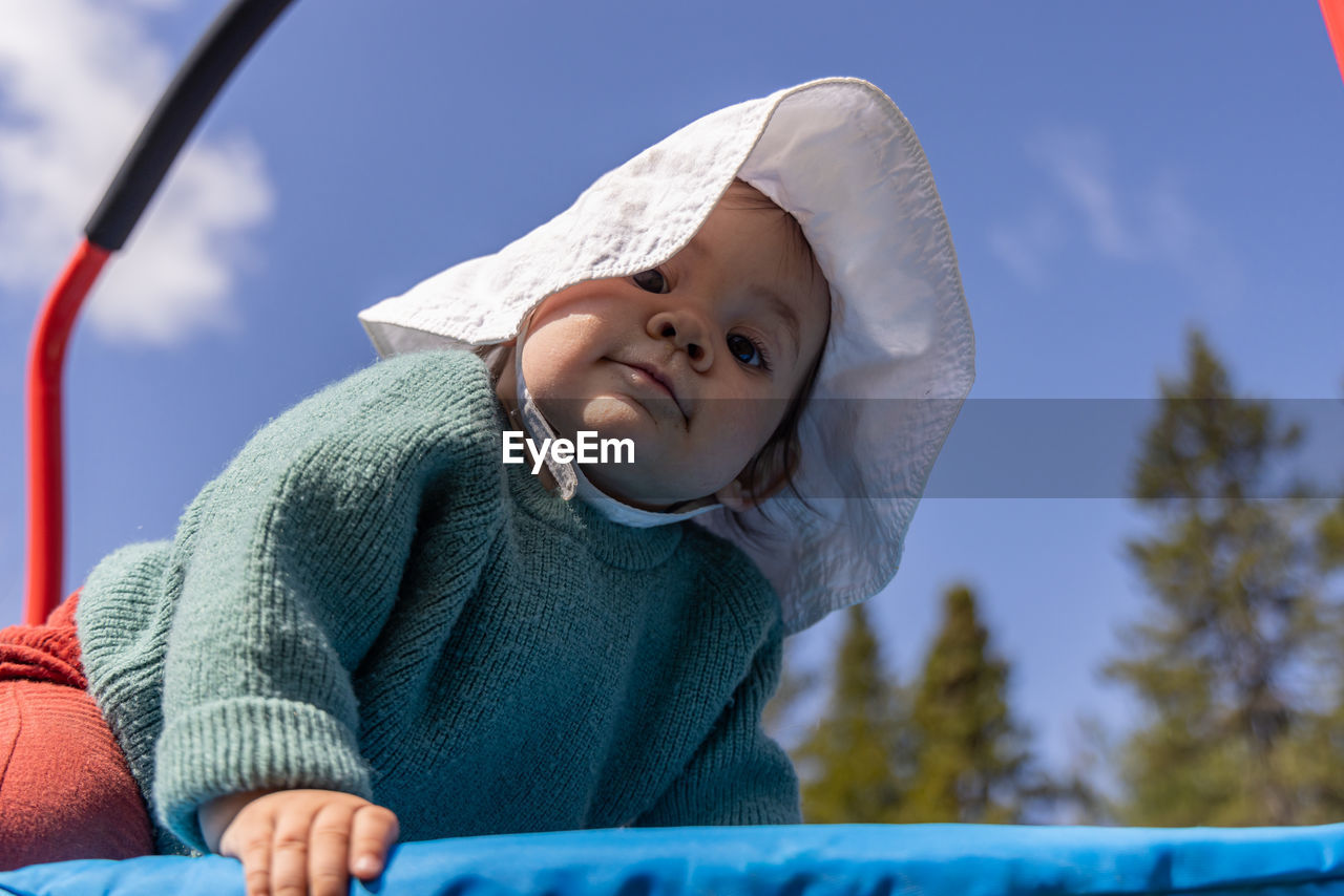 portrait of young woman sitting on slide at park