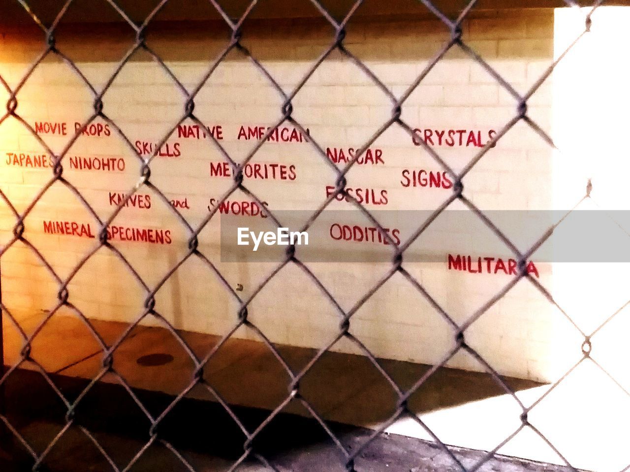 FULL FRAME SHOT OF TEXT ON CHAINLINK FENCE AGAINST BLURRED BACKGROUND