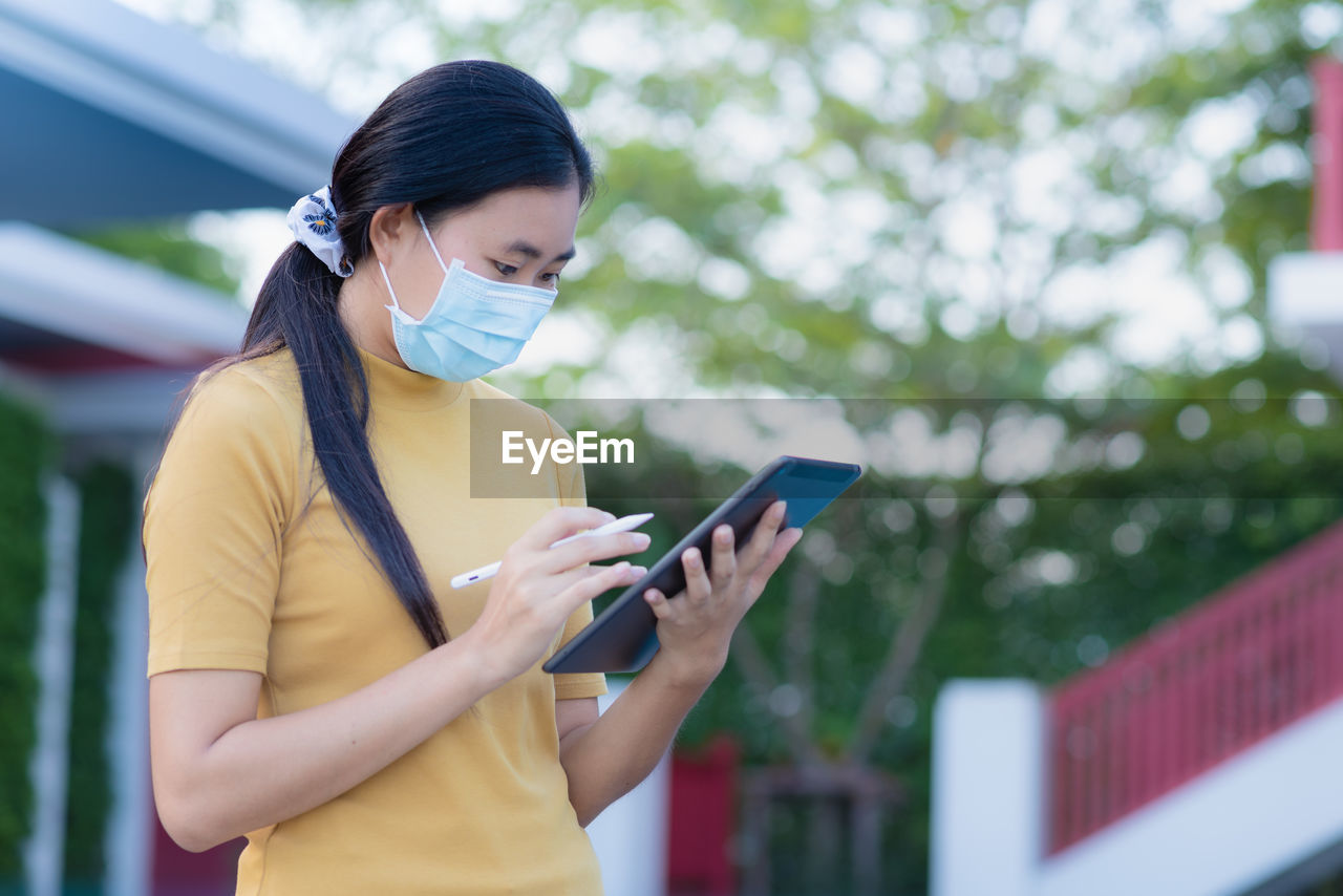 YOUNG WOMAN USING MOBILE PHONE AT CAMERA