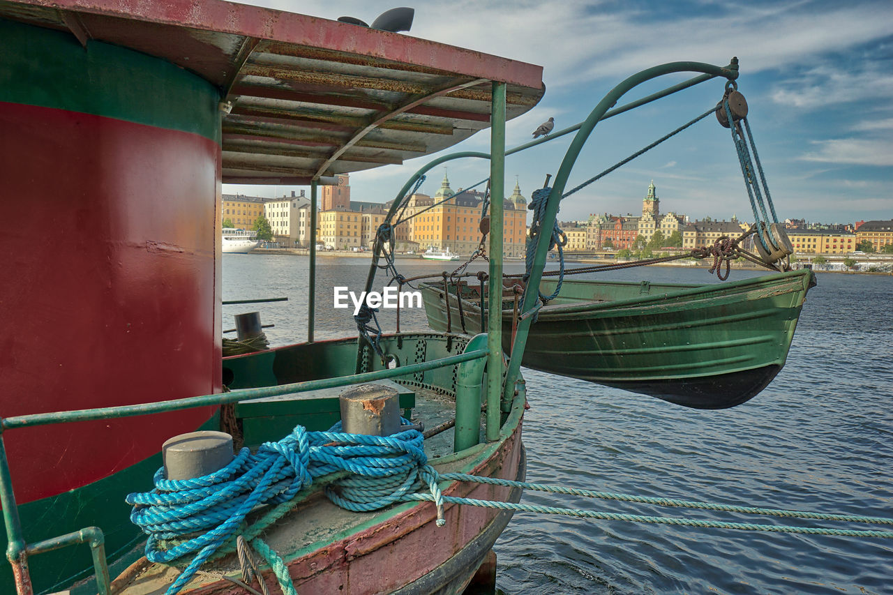 Fishing boats moored at harbor against sky