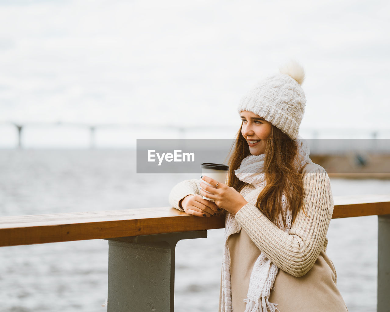 Young woman holding coffee while standing outdoors during winter